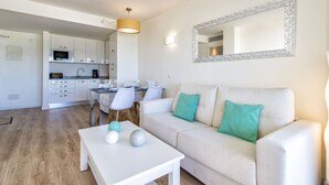 A modern living room with a sofa, a coffee table, and a dining area with chairs and a table. - APARTMENT IN CALA MILLOR, Modern, DIRECTLY ON THE BEACH, SEAVIEW, Wifi Incl, (Cala Millor)