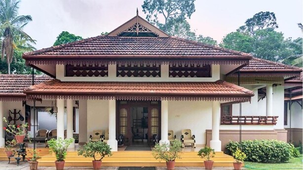 A traditional building with a tiled roof and a porch with potted plants. - Crystal Homestay by Vista Rooms (Virajpet)