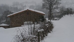 Un bâtiment en pierre doté d’un toit en pente, entouré d’un paysage enneigé et d’arbres.