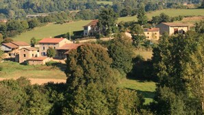 Un village rural aux maisons en pierre, entouré de champs verdoyants et de collines.
