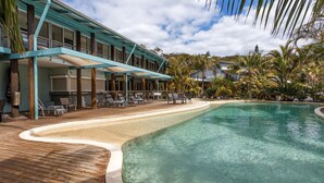 A resort with a pool, lounge chairs, and a covered area with tables and chairs. - Mobys Beach House # 11 (Boomerang Beach)