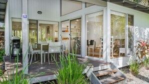 A modern house with a patio area, a dining table, and chairs. - Mobys Beach House # 11 (Boomerang Beach)