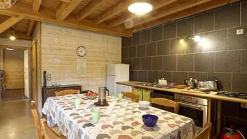 A cozy kitchen and dining area with wooden beams, a tiled backsplash, and a table set with dishes and a kettle.