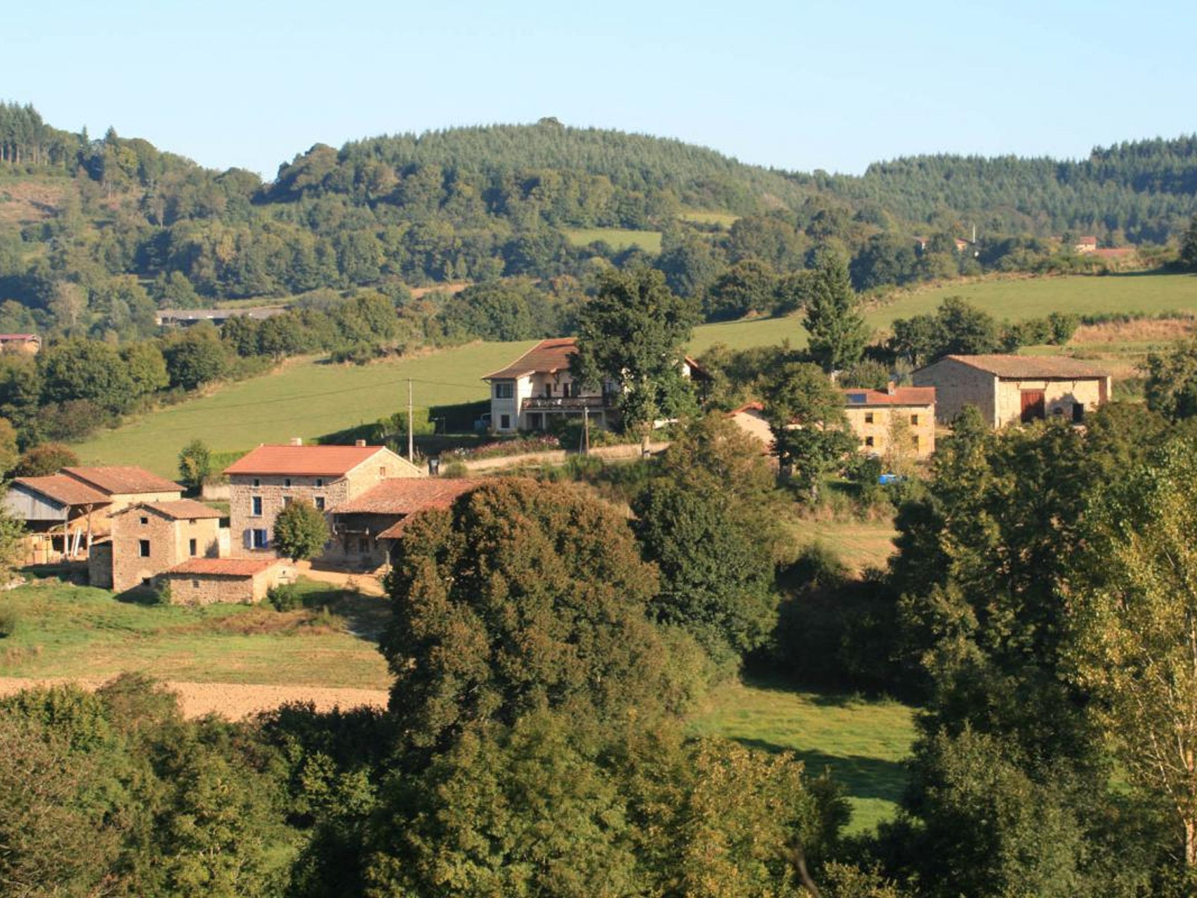 Un borgo rurale con edifici in pietra e uno sfondo collinare.