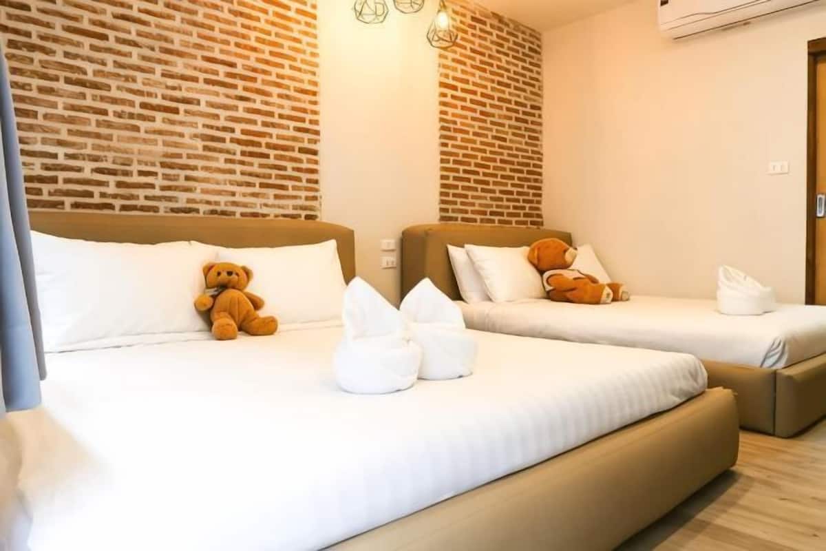 Een hotelkamer met twee bedden, een bakstenen muur en een houten vloer.