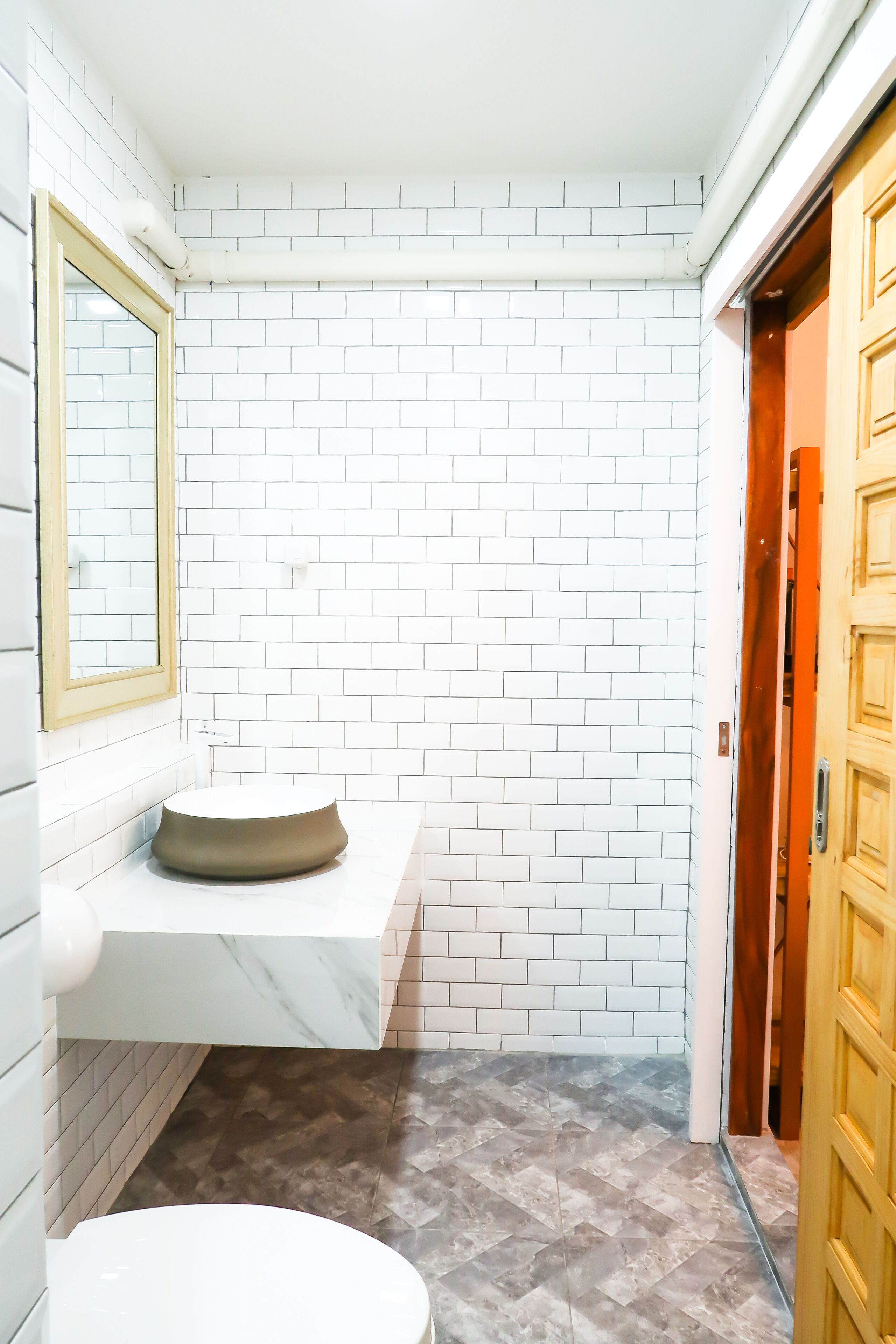 A bathroom with white brick walls, a marble sink, and a toilet.