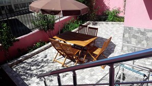 An outdoor patio with a wooden table and chairs, a brown umbrella, and a metal railing. - Golden Life Apart Otel (Istanbul)