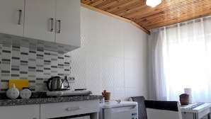 A compact kitchen with a microwave, toaster, and small refrigerator. There is a dining table with chairs and a window with curtains. - Golden Life Apart Otel (Istanbul)