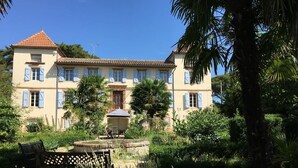 A large, two-story building with a symmetrical facade, a central entrance, and a small fountain in the courtyard. - Domaine de Menerque (Lisle-sur-Tarn)