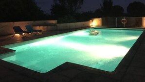 A rectangular swimming pool with a lighted edge, surrounded by a low wall and a metal fence. - Domaine de Menerque (Lisle-sur-Tarn)