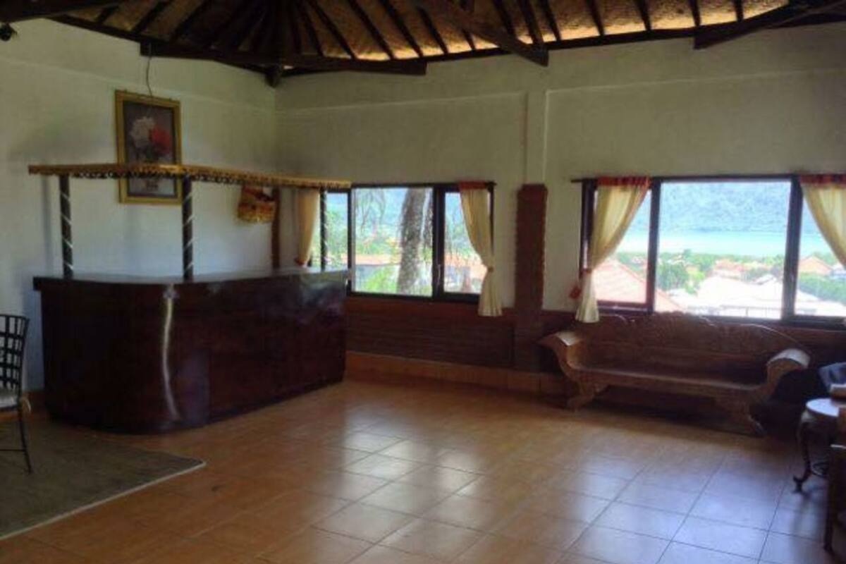 A room with a wooden reception desk, a bench, and large windows with curtains.
