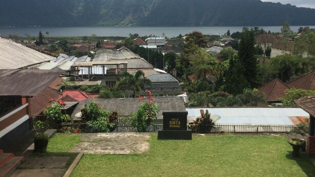 A residential area with a grassy lawn, a manhole cover, and a sign reading "Villa Sinta Bedugul." - Villa Sinta (Baturiti)