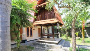 A traditional wooden house with a balcony, surrounded by trees and a small garden. - Bantan Guest House (Tibubeneng)