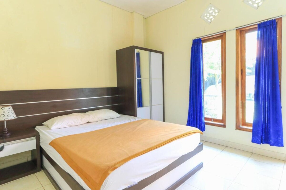 A bedroom with a bed, a nightstand, a wardrobe, and a window with curtains.