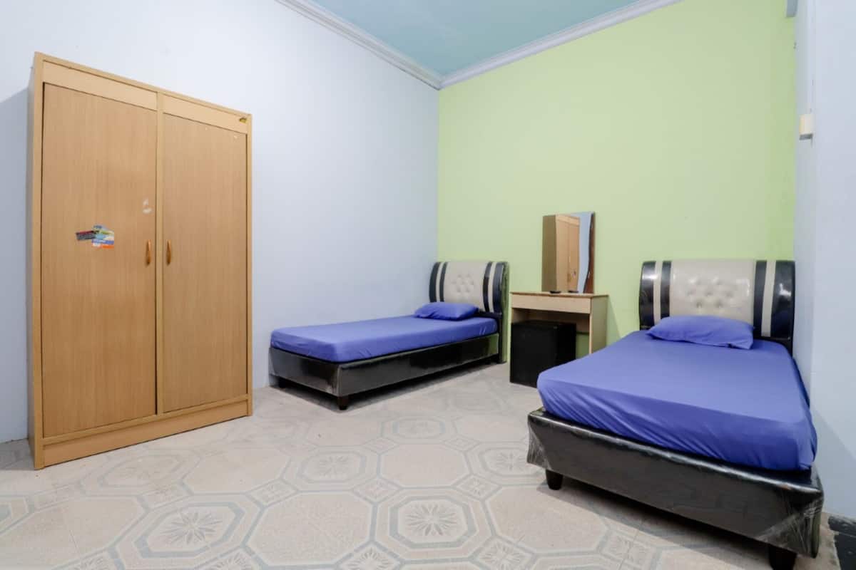 A room with two beds, a wardrobe, and a small table.