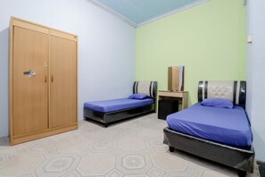 Habitació amb dos llits, un armari i una taula petita.