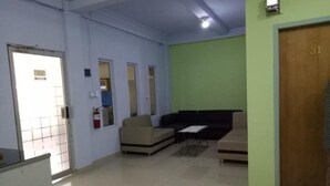 Zona de espera con mostrador de recepción, extintor y pared verde con una puerta marcada '31'.