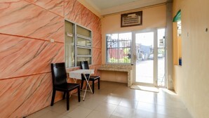 Una habitación con pared de mármol, una ventana con vistas y una puerta que da al exterior.