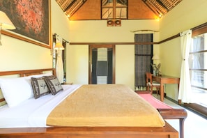 Une chambre avec un grand lit, une tête de lit en bois et une vue sur l’extérieur.