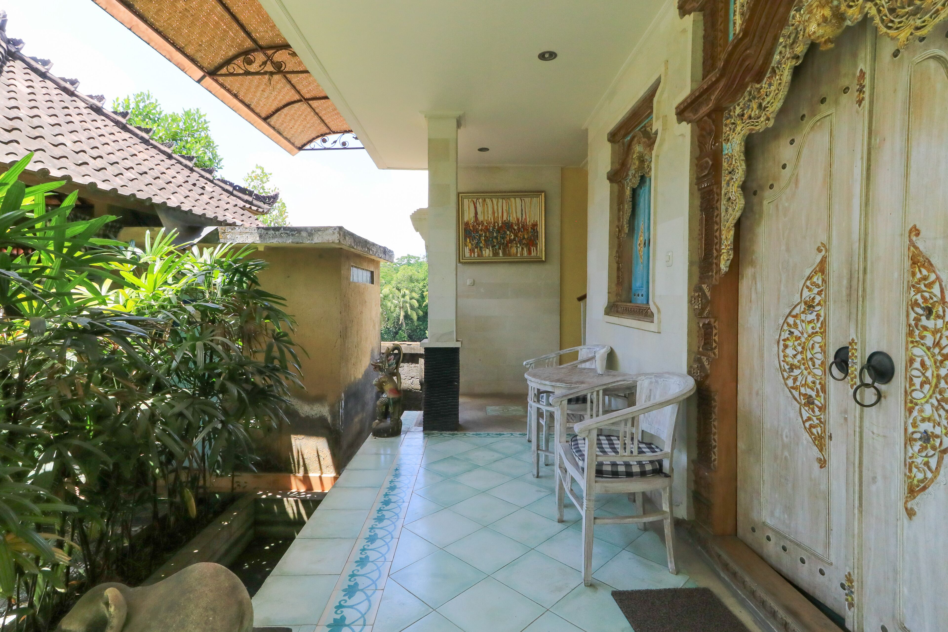 A covered patio area with a tiled floor, a white table with chairs, and a decorative door with intricate designs.