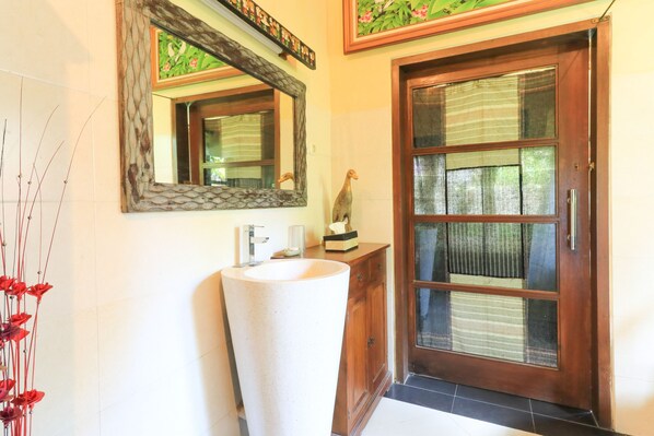 A bathroom with a large sink, a mirror, and a wooden cabinet.