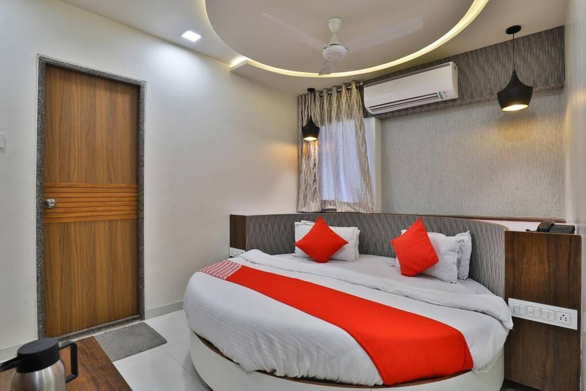 Une chambre d’hôtel moderne dotée d’un grand lit, d’une porte en bois, d’un climatiseur et d’un ventilateur de plafond.
