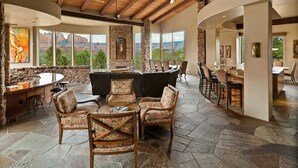 Un interior espacioso con chimenea de piedra, mobiliario exterior y amplias ventanas con vistas a la montaña.