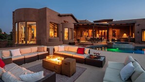 Un espacio al aire libre moderno con piscina, zonas de estar y un muro de piedra.