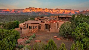 Un edificio de varios pisos con un patio interior, rodeado de árboles y un telón de fondo montañoso.