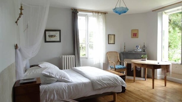 A bedroom with a bed, a chair, a table, and a window. - Moulin de la Papeterie Chambres d'hôtes (La Creche)