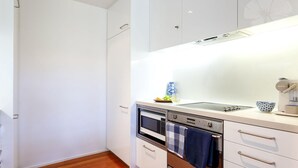 A modern kitchen with white cabinetry, a built-in oven, microwave, and a coffee maker.