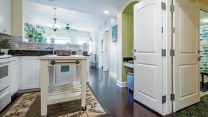 A kitchen with white cabinets, a central island, and a dining area with a table and chairs.