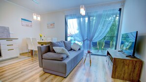 A modern living room with a sofa, a wooden coffee table, a TV, and a balcony with a view. - HelApart - NATURALnie że Hel (Hel)