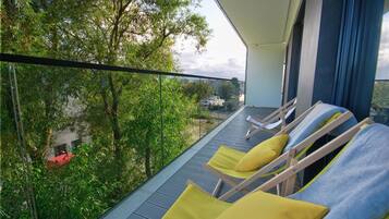 Un balcon avec deux fauteuils de jardin, l’un doté d’un coussin jaune et l’autre d’un coussin bleu.