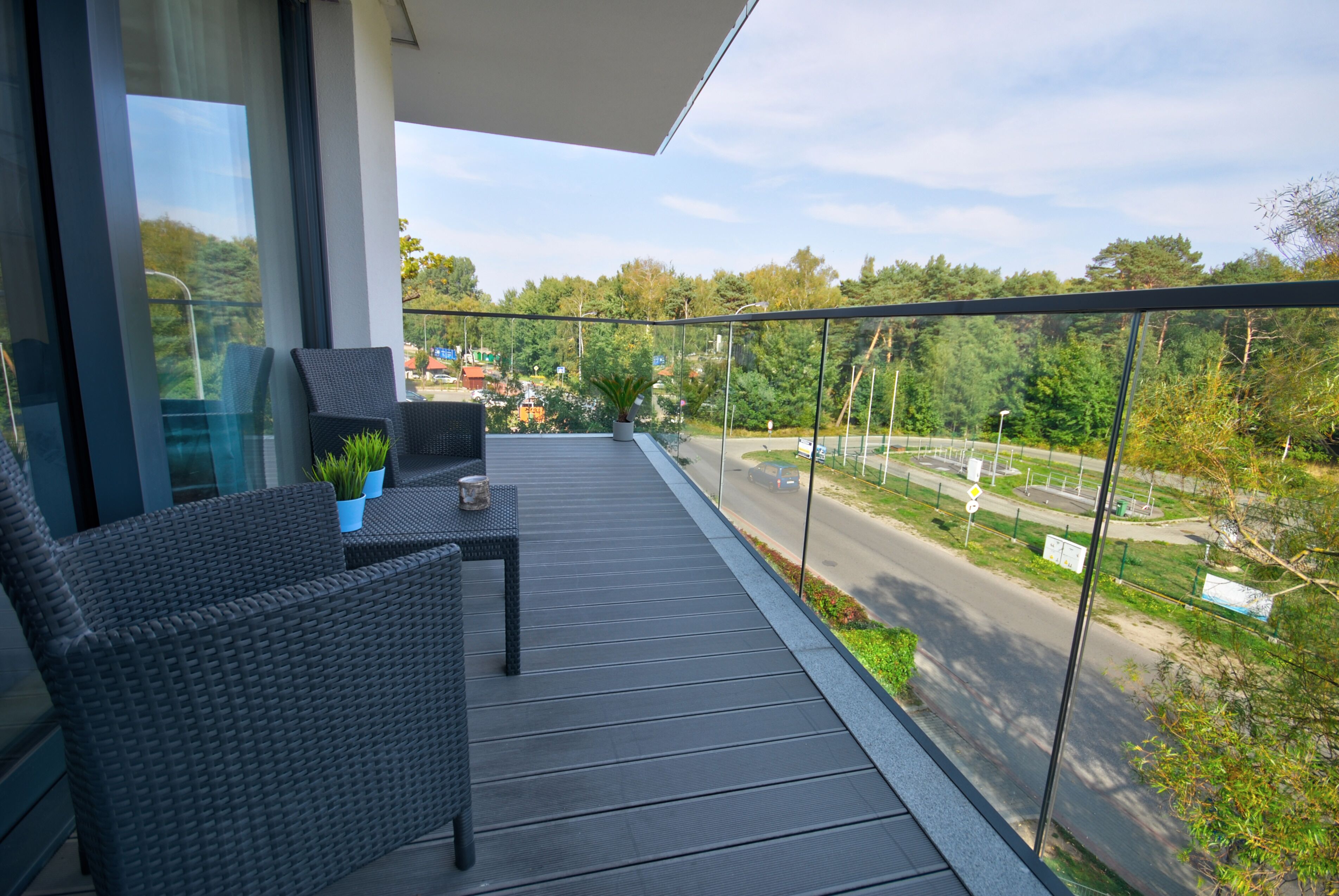 A balcony with wicker furniture, a small table, and potted plants.