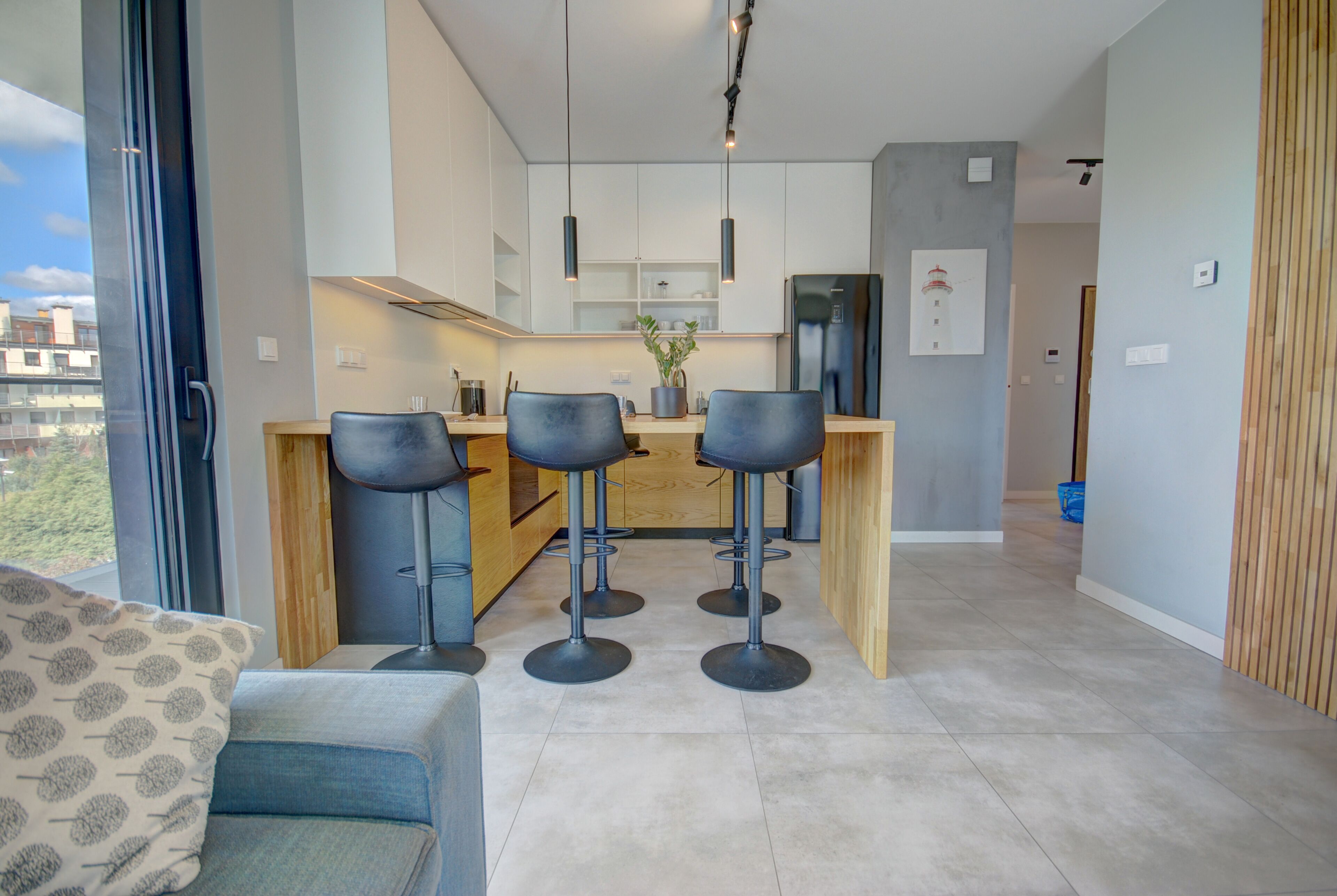 A modern kitchen with a central island, bar stools, and pendant lighting.
