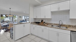A modern kitchen with white cabinetry, granite countertops, and a stainless steel sink. - The Good Life 5bed/4bath wth private pool 30 ft of dock and 2 kayaks included (Marathon)