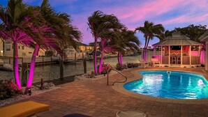 A pool area with palm trees, a gazebo, and a view of a body of water. - The Good Life 5bed/4bath wth private pool 30 ft of dock and 2 kayaks included (Marathon)
