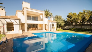 Uma casa moderna de dois andares com piscina, móveis de jardim e um jardim bem cuidado.