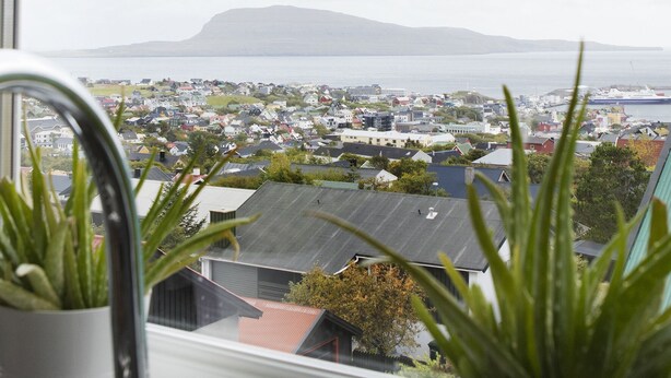 A view from a window overlooking a town with houses and a distant mountain. - Mørk Apartments (Tórshavn)