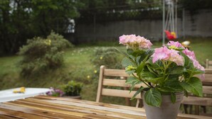 A wooden table with a potted plant of pink flowers. - Mørk Apartments (Tórshavn)