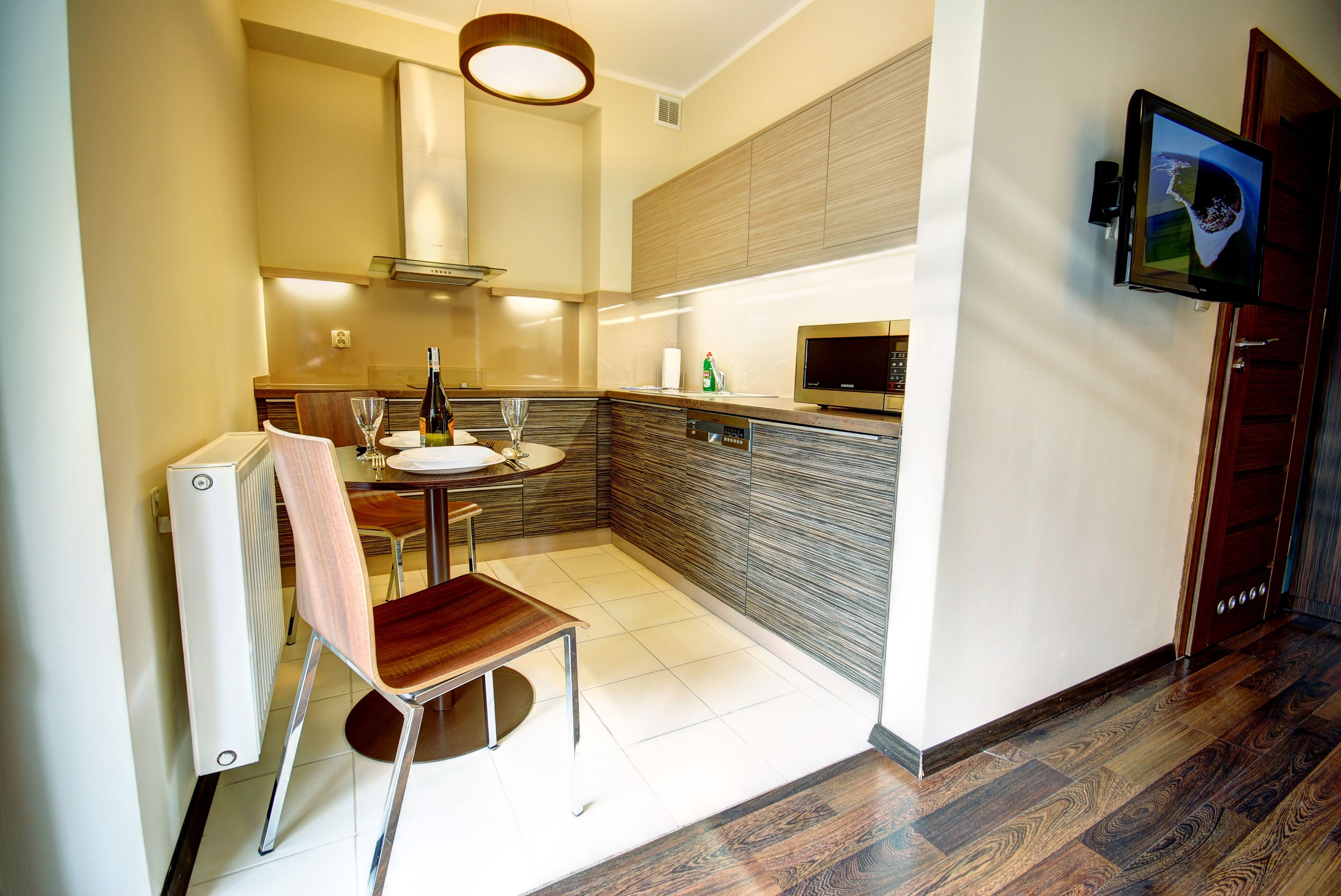 A compact kitchen with a dining area, a built-in microwave, and a TV mounted on the wall.