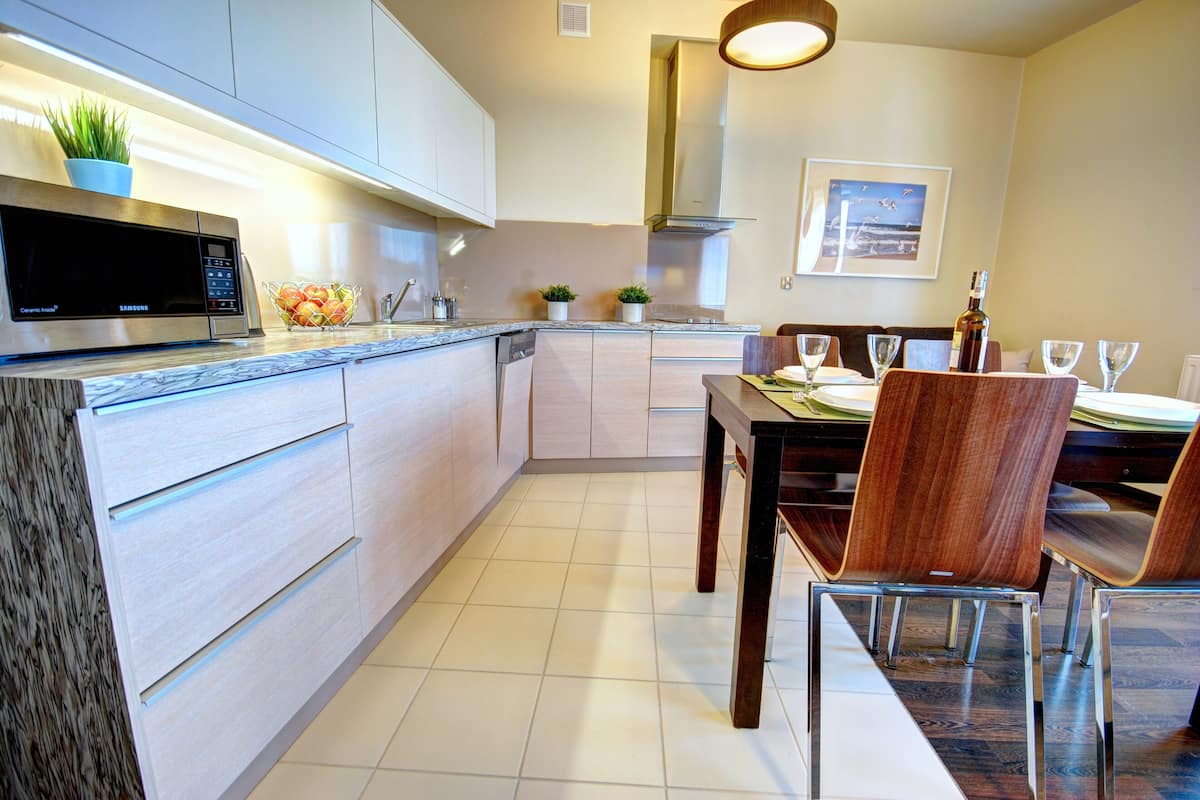 A modern kitchen with a built-in microwave, a dining table with chairs, and a small dining area.