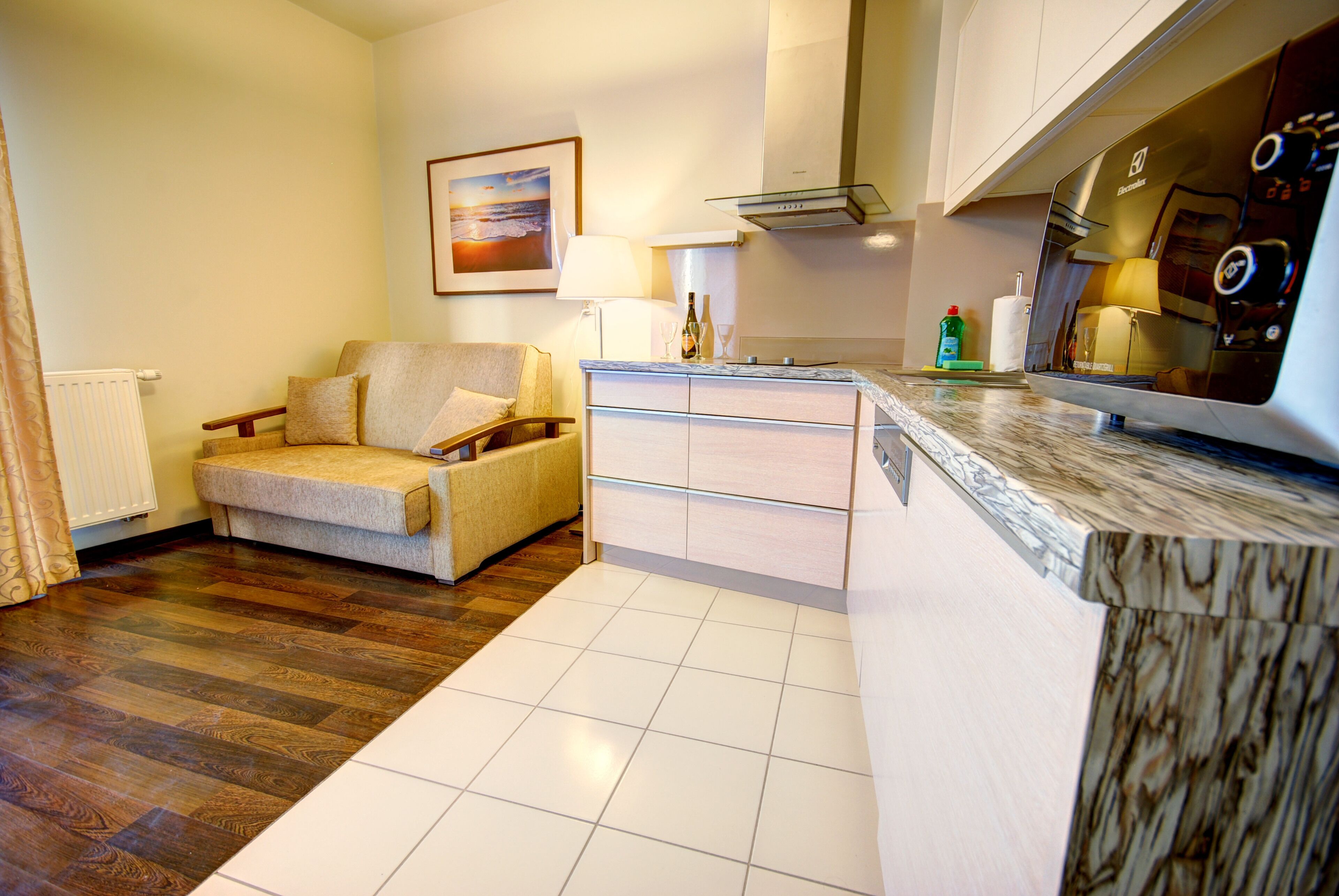 A modern living room with a sofa, a dining area with a kitchen island, and a large window.