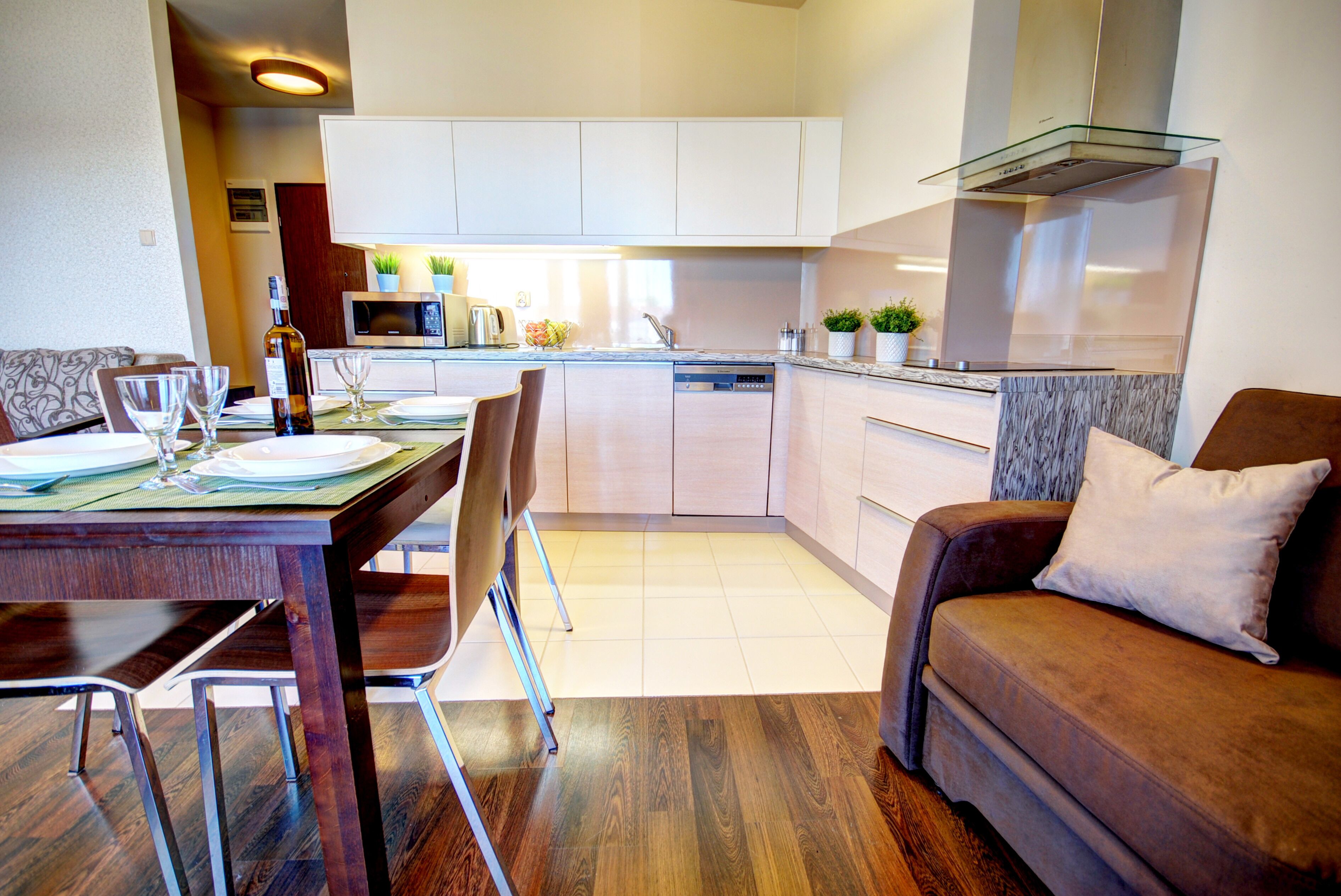 A modern kitchen with white cabinets, a built-in oven, and a glass range hood.