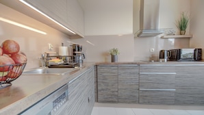 A modern kitchen with a dishwasher, a coffee maker, a microwave, and a sink. - HelApart - Apartamenty Foka (Hel)