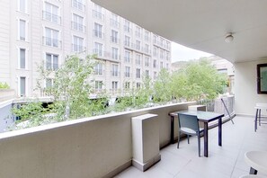 A balcony with a table and chairs, overlooking a building with multiple windows and balconies.