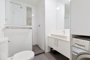 A modern bathroom with a shower, toilet, and a Bosch washing machine.
