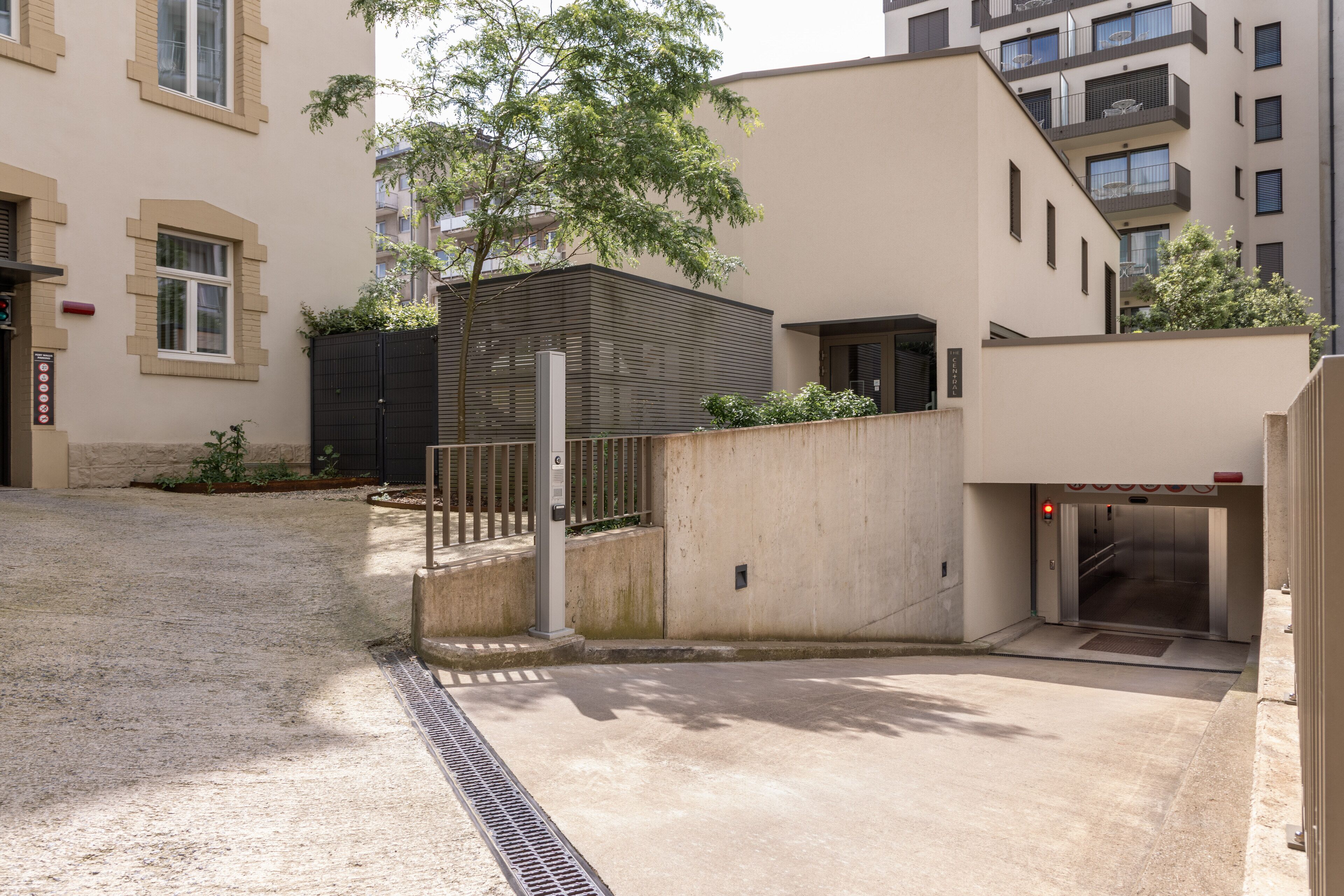 Ein modernes Gebäude mit geschlossenem Eingang, einer Treppe und einem überdachten Bereich.