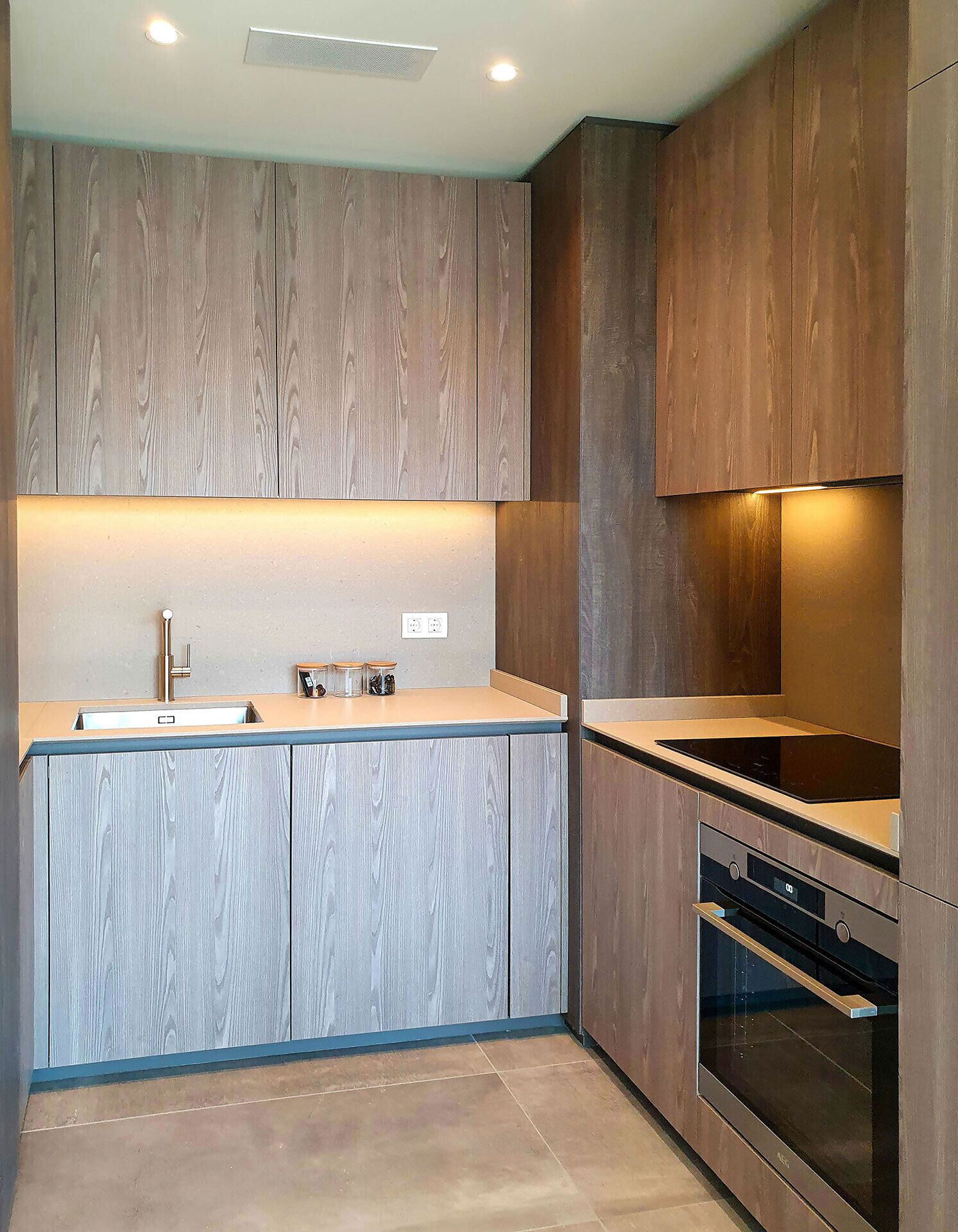 A modern kitchen with wooden cabinets, a stainless steel sink, and an oven.